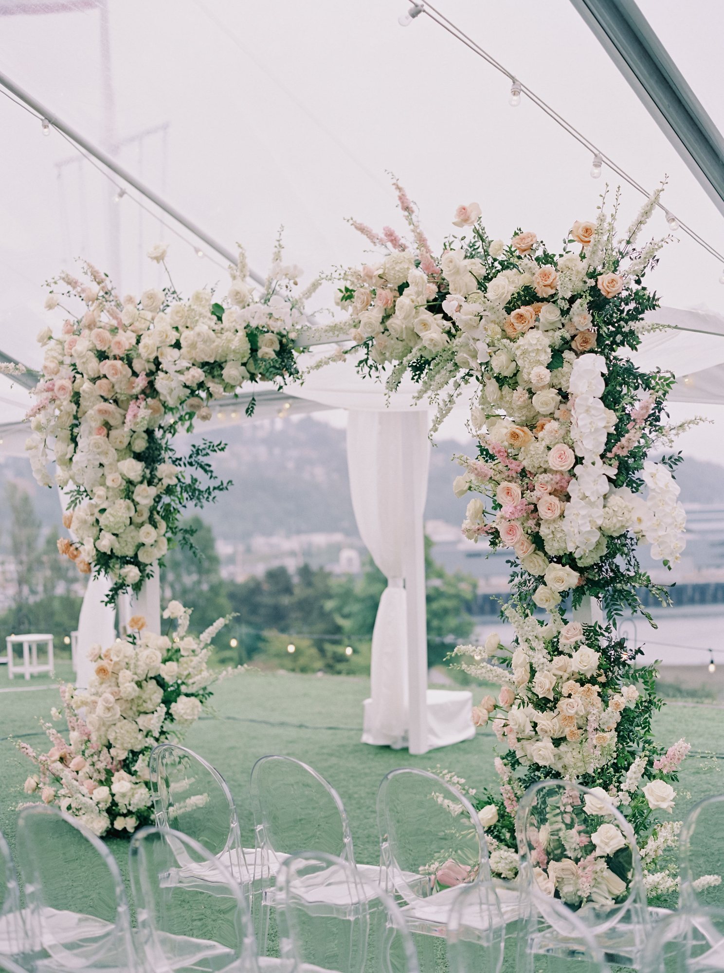 Blush and ivory floral ceremony arch in a tented wedding