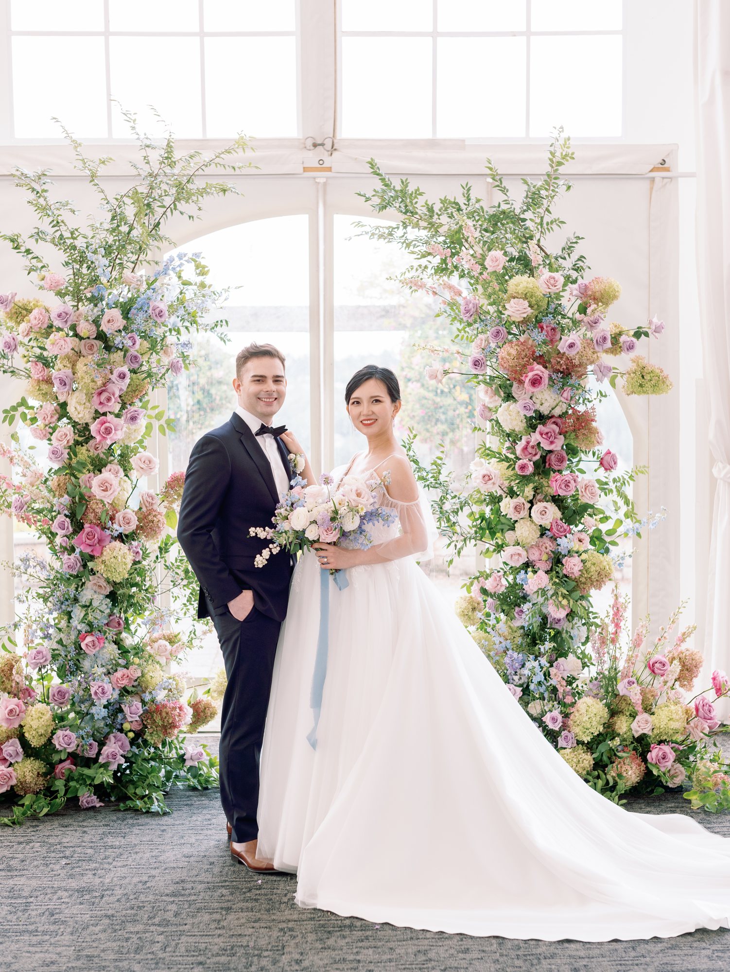 Bride and groom at a pink and white floral wedding arch